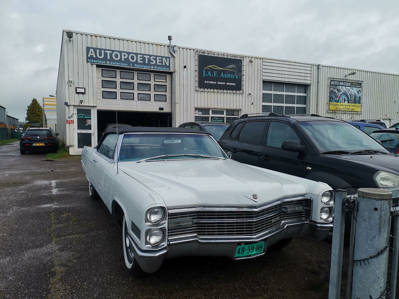 Een witte klassieke Cadillac cabriolet op het terrein voor de werkplaats